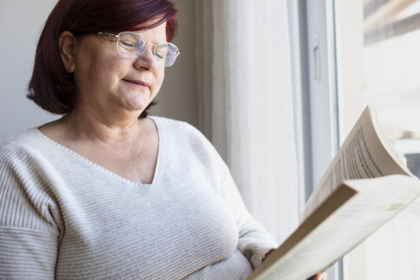 戴眼镜的老妇人躺在沙发上看书图片下载