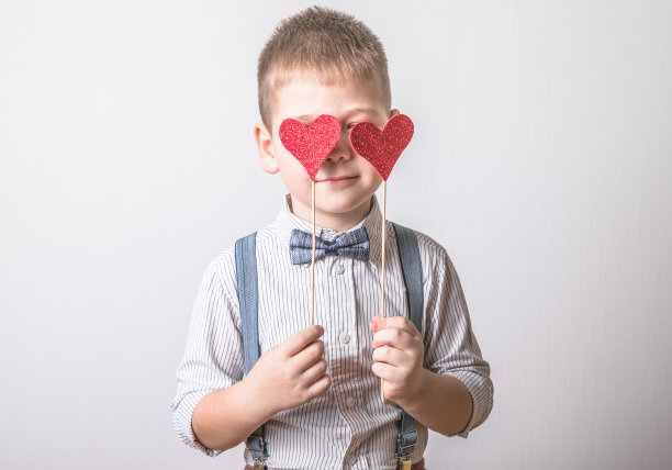 5岁的小男孩面带微笑，手拿一颗象征着爱、家庭、希望的红心。关于保护家庭和孩子的情人节卡片或社会海报的背景。图片下载