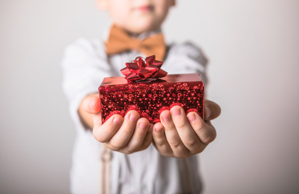 5岁微笑的小男孩送红礼物，情人节。赠送和接收节日礼盒。圣诞送礼时间概念。图片下载