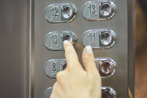 一个女人的手指在电梯面板上按楼层按钮的特写图片下载