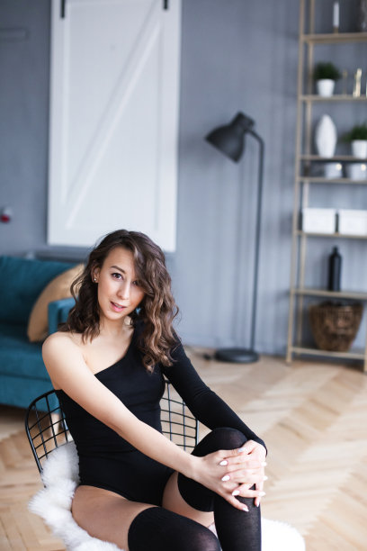 美丽的女人与完美的身体在黑色内衣在椅子摆姿势。舞者在隔离。图片下载