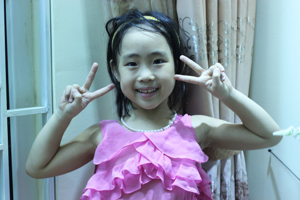 一个可爱的小女孩在家里举起双手，脸上洋溢着幸福图片下载