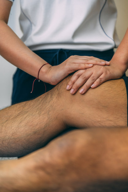 理疗师把两只手放在病人的膝盖上。男性病人与女性理疗师。图片下载