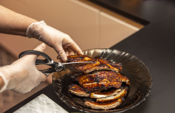 近距离观看女性切烧烤排骨与厨房sax。图片下载