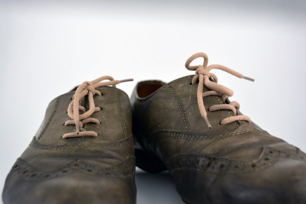女式皮鞋位于白色背景上。平跟灰色鞋带的牛津鞋。灰色的女鞋在系着，不知不觉。图片下载