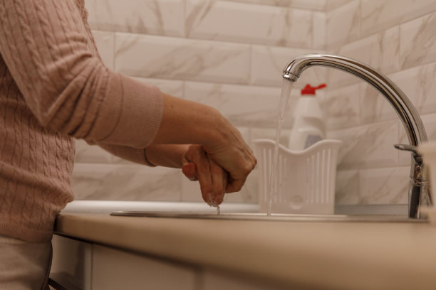 一个面目全的女人在厨房水槽上洗手图片下载