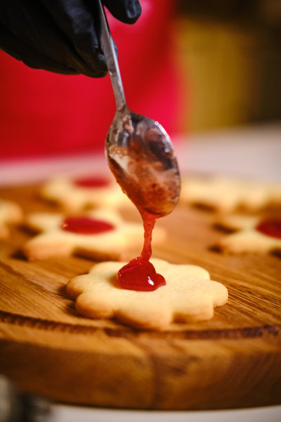 戴着黑手套的女性双手在饼干上涂果酱。圣诞快乐，恭贺新禧。近距离图片下载