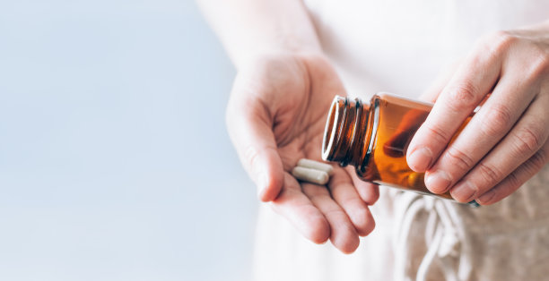 药片装在女性手上的瓶子里。健康与医学图片下载