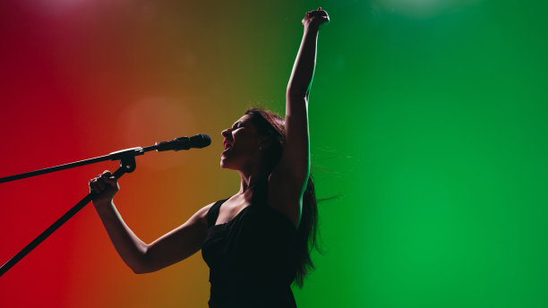 年轻女歌手的肖像孤立在绿色红色的背景。图片下载