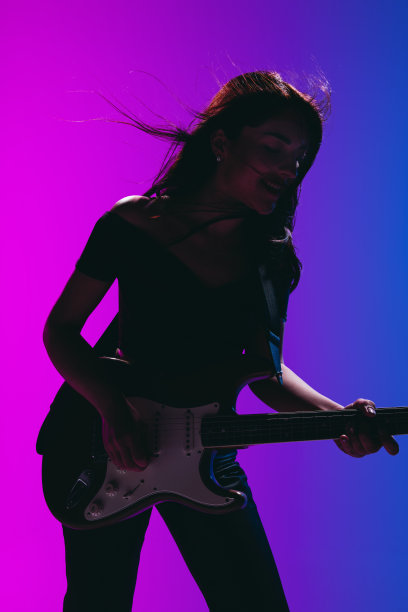剪影的年轻女吉他手孤立在梯度背景霓虹灯。图片下载