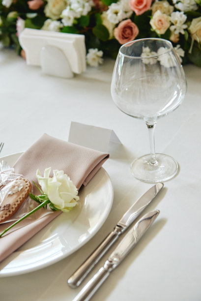 空白宾客卡的桌子，白色盘子与米色餐巾，玫瑰，心形和餐具的桌子，复印空间。婚宴场地设置。餐厅婚宴餐桌图片下载