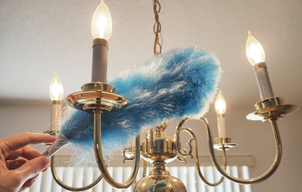 蓝色羽毛掸子正在清理布满灰尘的枝形吊灯图片下载