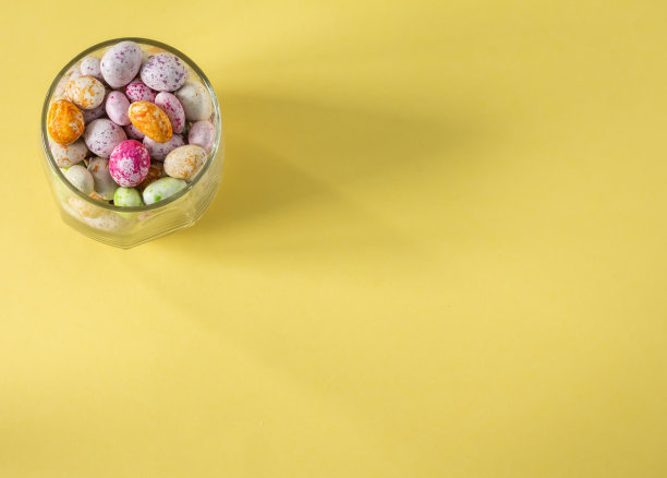 玻璃杯与彩色糖果在黄色背景顶视图平砌体与空间的复制图片下载