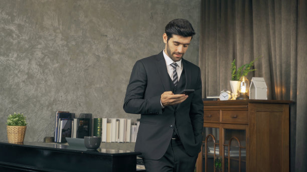 微笑的商业中东人，CEO人在家里工作与电脑笔记本电脑和在移动智能手机在技术设备交流的概念。图片下载