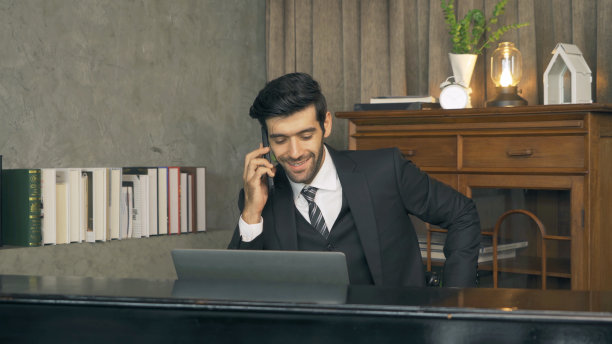 微笑的商业中东人，CEO人在家里工作与电脑笔记本电脑和在移动智能手机在技术设备交流的概念。图片下载