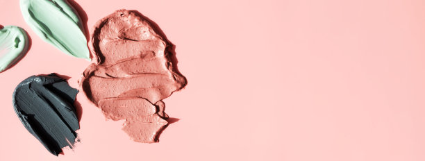 各种面部粘土化妆面具涂抹在粉红色的背景与复制空间水平横幅格式。化妆品纹理黑色，粉色和绿色粘土图片下载