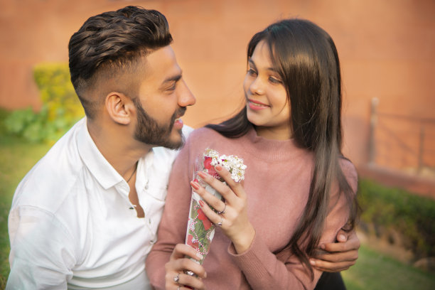 一对快乐浪漫的年轻情侣坐在公园里。图片下载