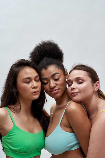 工作室肖像的三个性感的多民族妇女在彩色内衣摆姿势与眼睛封闭隔离在光背景图片下载