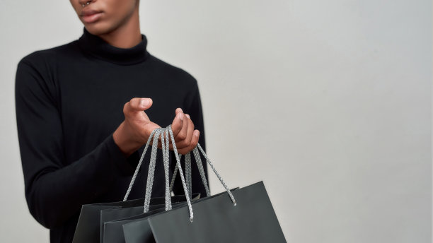 一个年轻的非裔美国人手里拿着购物袋图片下载