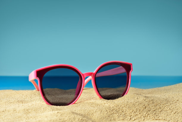 近距离看沙滩上的粉红色眼镜。蓝色海水背景下的海滩上的眼镜。夏季，海洋和度假概念。图片下载