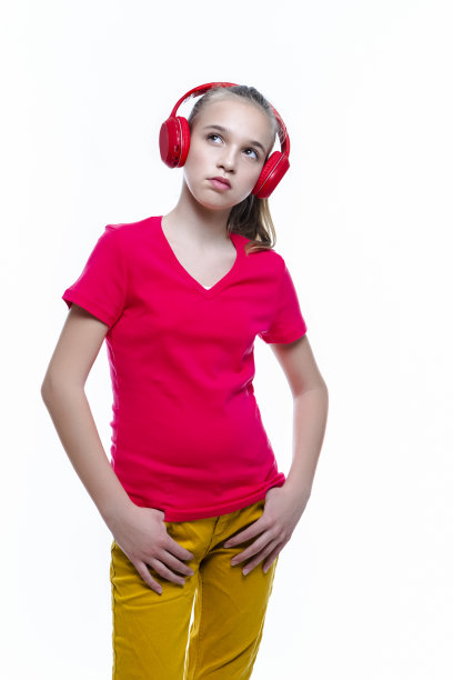 正面的白人少女肖像与红色耳机享受音乐。摆姿势与白色。垂直的形象定位图片下载