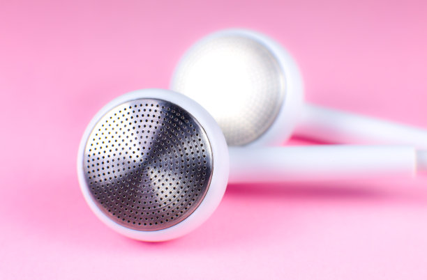 白色耳机躺在粉红色的背景上。现代音乐的概念。音频技术。近距离的照片。图片下载