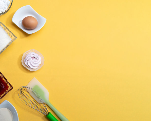 配料和制作棉花糖的工具。糖，果酱，面粉，打蛋器，抹刀，棉花糖，鸡蛋，黄色背景，文字空间。有选择性的重点。图片下载