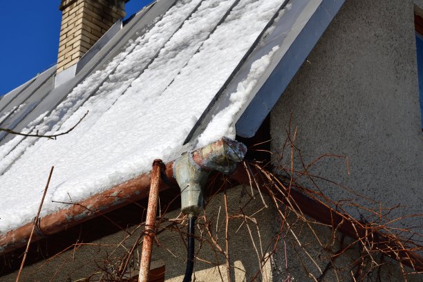 融化的雪通过排水管从屋顶滴落到地面图片下载