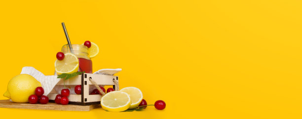 “排毒水果”是一个用新鲜的樱桃、柠檬和醋栗叶榨汁的水杯，背景是黄色。清爽的夏日自制鸡尾酒放在木托盘上。生态食品。图片下载