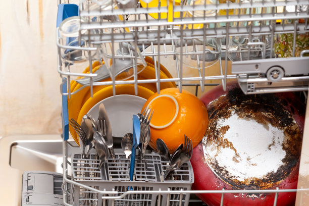 许多不同的盘子在一个开放装载洗碗机的侧面视图。洗餐具和各种餐具概念简单，自然，家庭日常杂务。右边是烧焦的平底锅，没有人图片下载