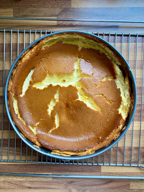 普通的纽约风格整块芝士蛋糕在烤盘和木质表面上新鲜烘焙。图片下载