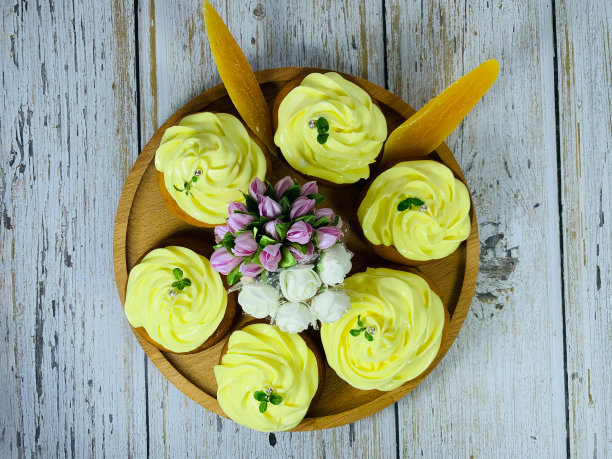 木圆盘子上放着奶油的纸杯蛋糕。图片下载