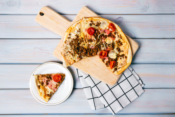 木桌上有培根、牛肉、樱桃番茄和马苏里拉奶酪的披萨。图片下载