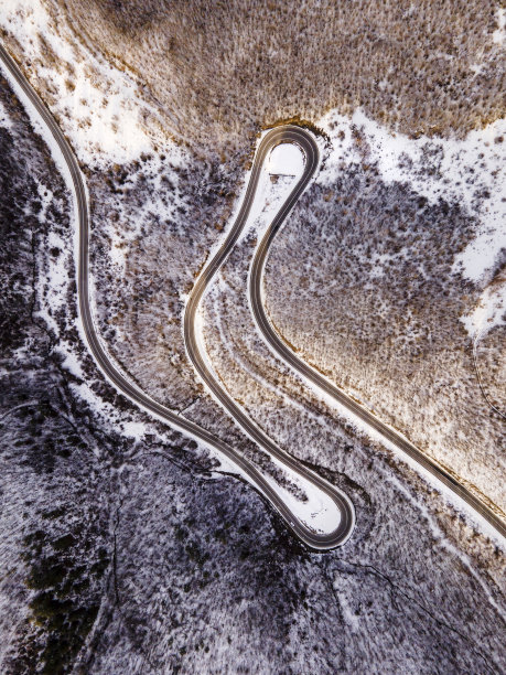 高角度鸟瞰无人机图像在弯曲的蛇形道路槽的树木和森林的山脉与白色的雪在冬天的一天在塞尔维亚附近的Knjazevac -旅行旅行度假概念图片下载