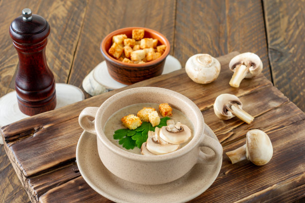 蘑菇奶油汤，配香草和香料，棕色碗放在木桌上。乡村风格图片下载