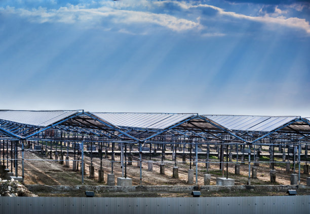 旧的温室重新安装了太阳能板，绿色能源，阳光穿过多云的天空图片下载