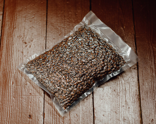 新鲜烘培的咖啡豆装在真空密封袋内，背景放在木板上图片下载