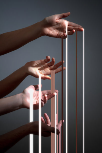 四个人的手握着光线的条纹，阳光在灰色的背景中孤立。图片下载