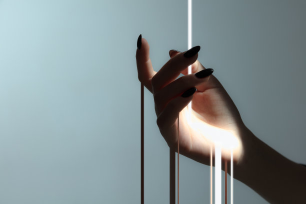 光线通过精致的女性手孤立在灰色背景。图片下载