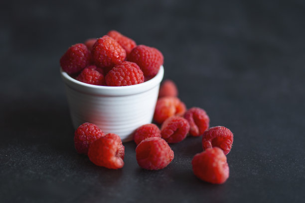 成熟的红莓在一个粘土碗在黑色的背景。红覆盆子在泥碗上的照片。高分辨率的产品。成熟的浆果碗。夏天甜的水果。图片下载