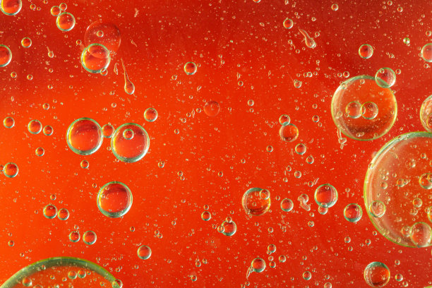 红色艺术的油滴浮在水面上。摘要油泡背景。微距镜头。石油泡沫会消失。图片下载