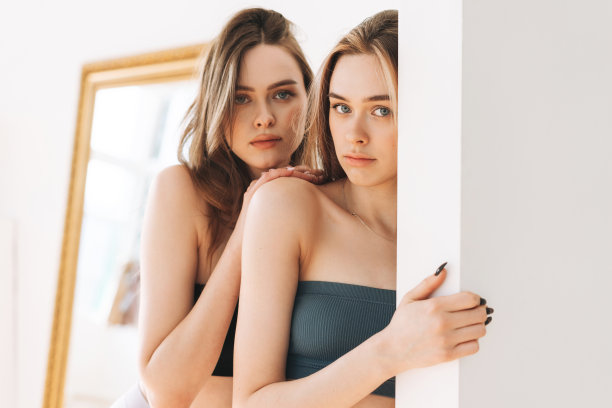 时尚美女模特两姐妹双胞胎美丽的女孩与长头发看着相机在明亮的工作室图片下载