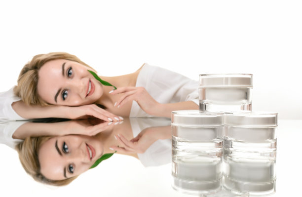 玻璃罐美容霜护肤和出焦点美丽的女人肖像与绿叶图片下载