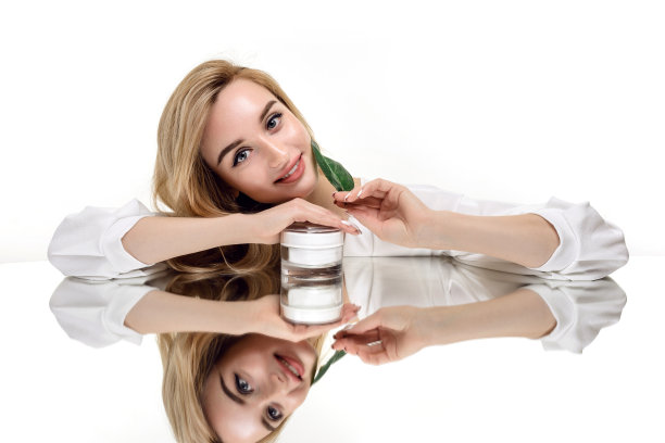 皮肤护理和有机化妆品的概念。美丽的女人肖像与化妆品霜和绿叶图片下载