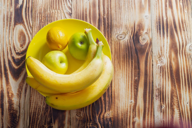 黄上黄的概念。整只黄色的柠檬，苹果和香蕉放在一个盘子里图片下载