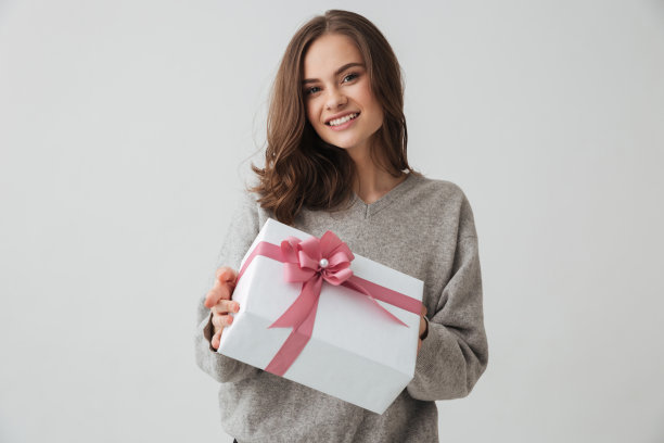 快乐的黑发女人在毛衣拿着礼盒图片下载