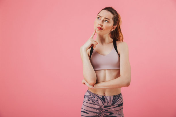 沉思的女运动员的姿势，触摸她的下巴和向上看图片下载