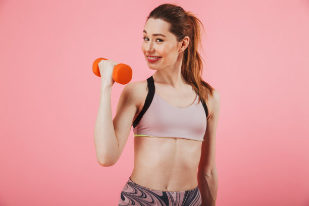 高兴的女运动员拿着哑铃，看着镜头做运动图片下载