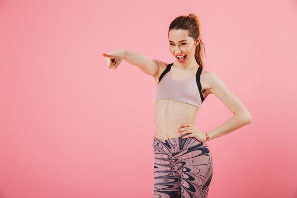 高兴的女运动员，手臂放在臀部，指向别处图片下载