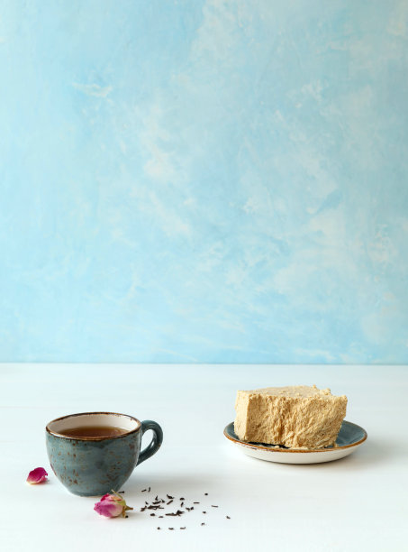 哈尔瓦和茶在一个不寻常的陶瓷盘子在一个蓝白色的背景图片下载